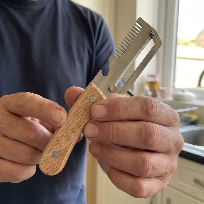 A man holds PeelPro with both hands by its wooden handle