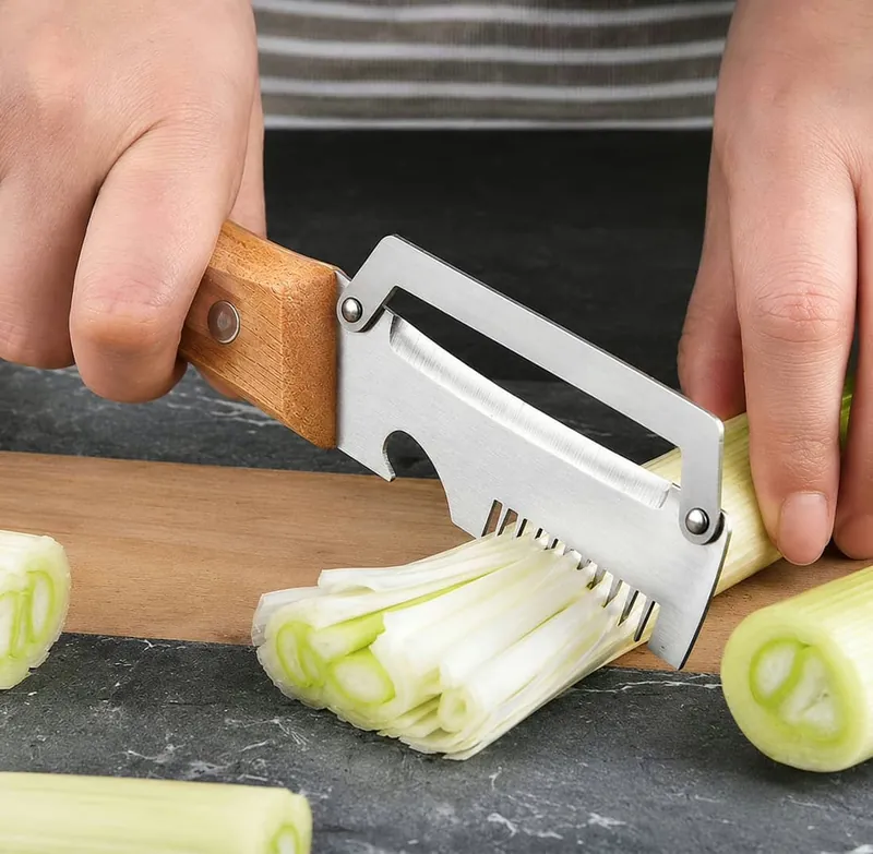 PeelPro on a wooden cutting board next to thin julienned strips of leek